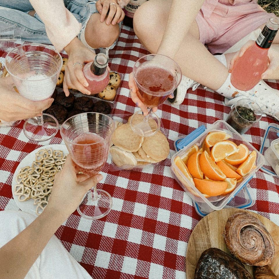 Picknick ovanifrån med rosévin och frukt på rödrutig duk